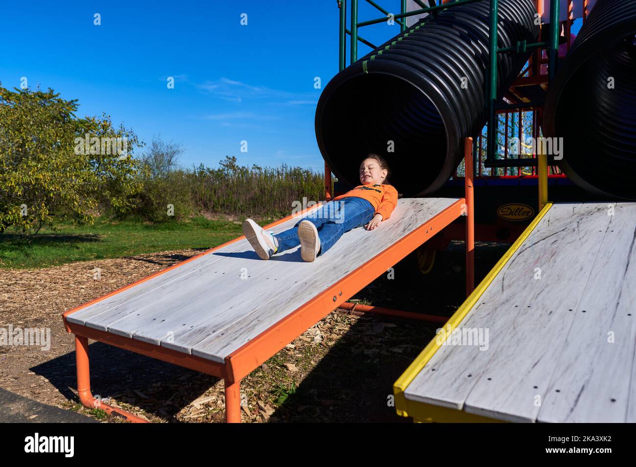 funny girl sliding down the slide at the farm fair on Halloween Stock Photo