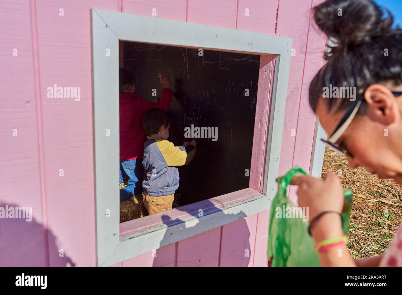 Kids running around and coloring in a chalk house at the farm fair on
