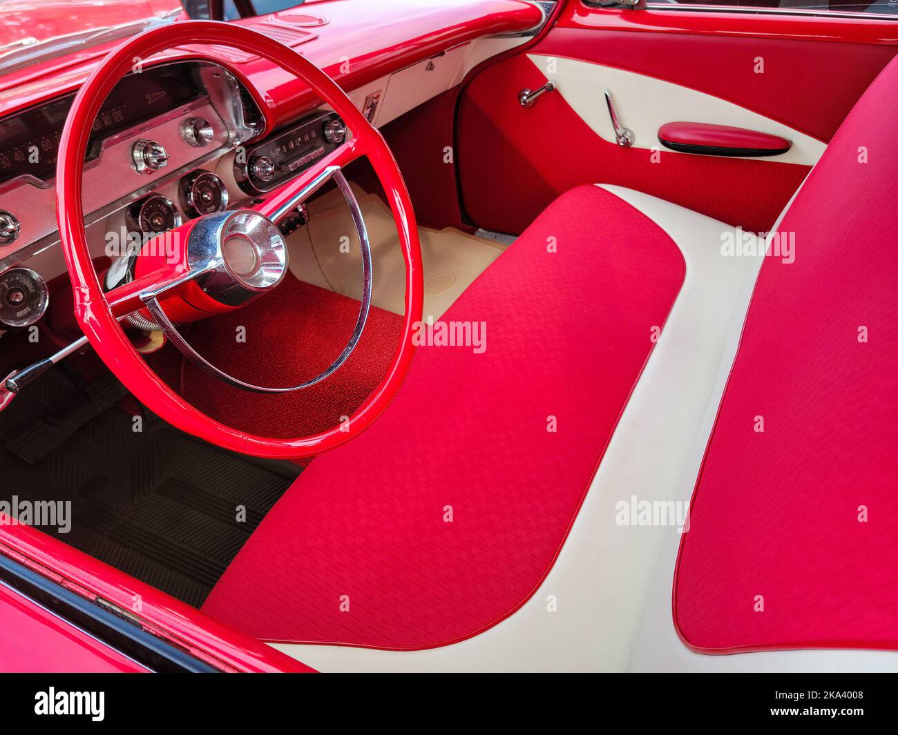 Bright red and white vintage car interior with bench seat and steering wheel Stock Photo