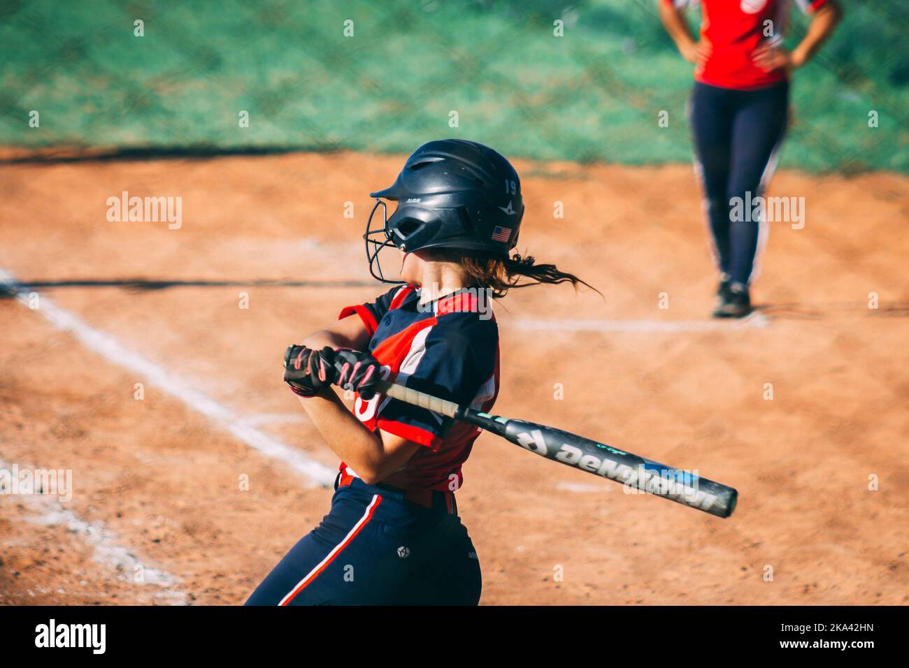 A back view of a female catcher ready to hit the ball in a baseball