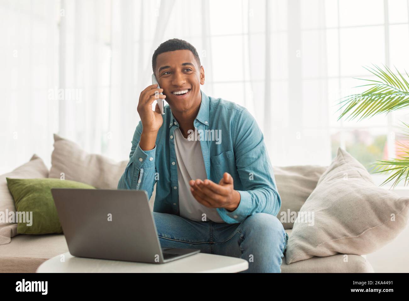 Glad busy millennial african american male with laptop making phone ...