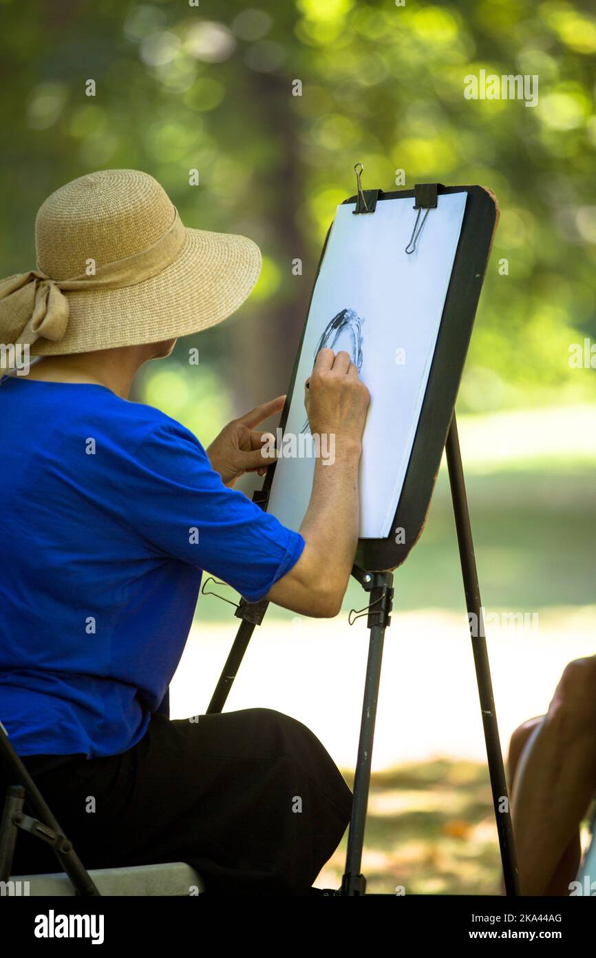 A female painter in a hat drawing on paper in the open air Stock Photo Alamy