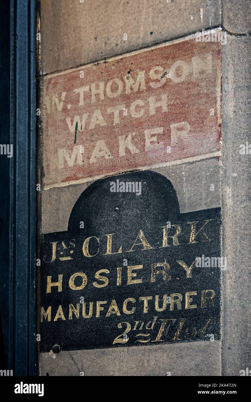 Ghost signs for a watchmaker and hosiery manufacturer in Edinburgh's Old Town. Stock Photo