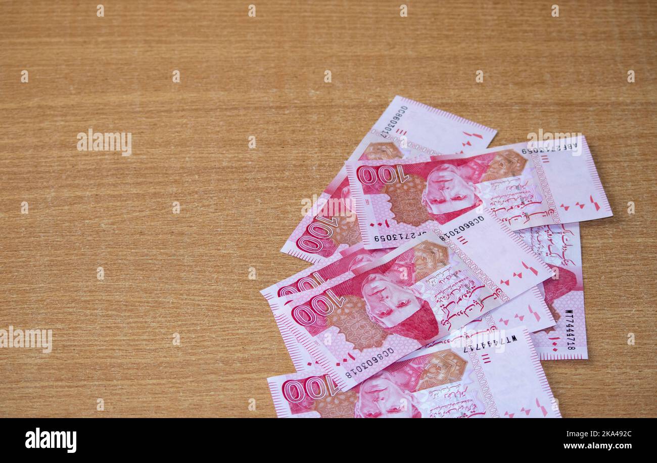 A closeup of the 100 Pakistani rupee currency bill on a wooden table Stock Photo