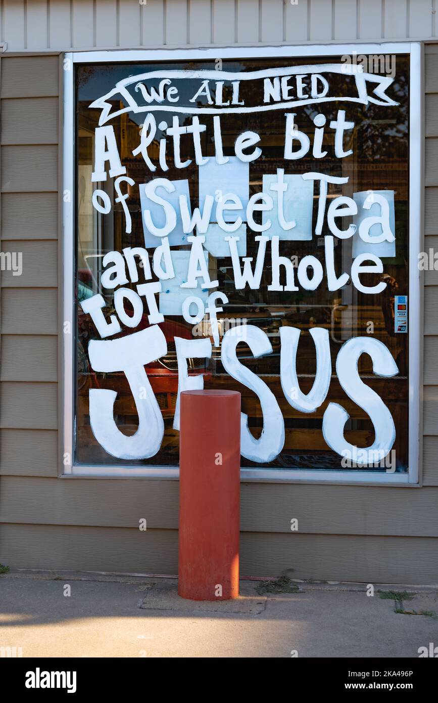 A sign on the window of a restaurant reads, We all need a little bit of sweet tea and a whole lot of Jesus. Stock Photo