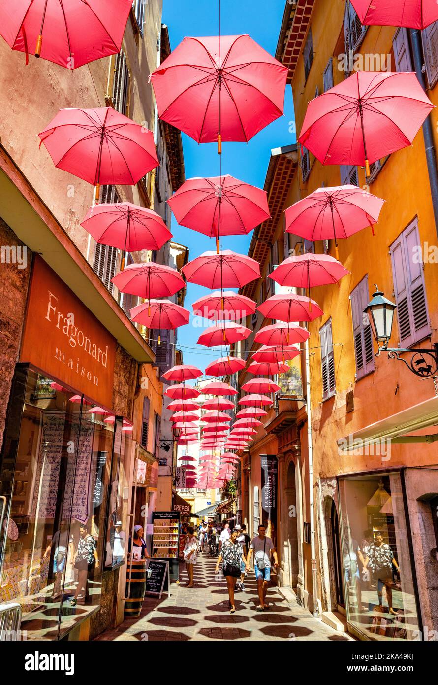 Grasse, France - August 6, 2022: Historic tenement houses and narrow streets decorated with pink umbrellas of old town quarter of perfumery city Stock Photo