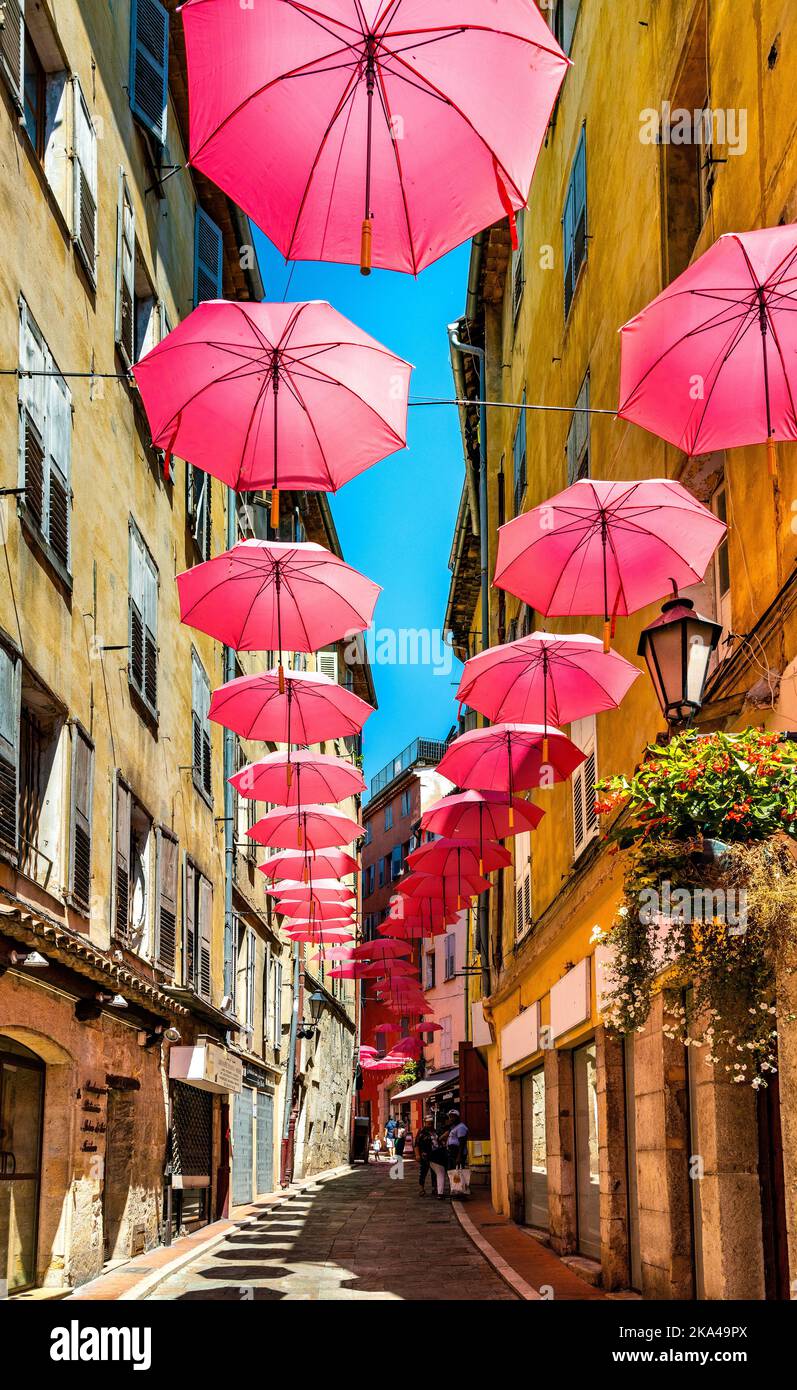 Grasse, France - August 6, 2022: Historic tenement houses and narrow streets decorated with pink umbrellas of old town quarter of perfumery city Stock Photo