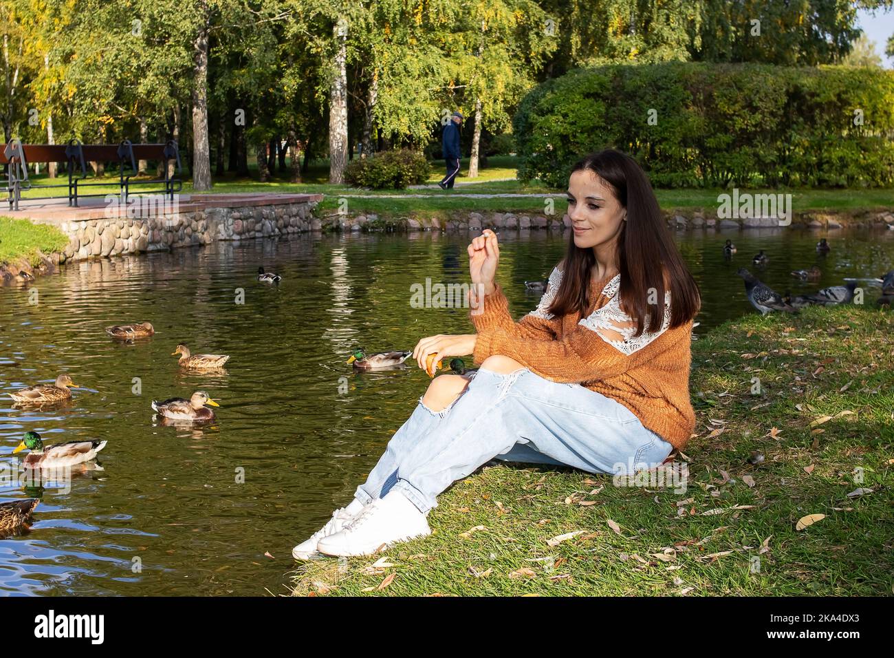 A girl sits on the shore of a pond in an autumn park Stock Photo - Alamy