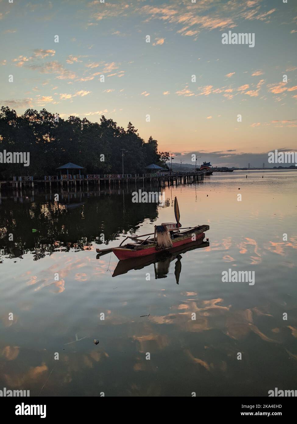 A beautiful view of a fishing boat on a reflective lake during sunset ...