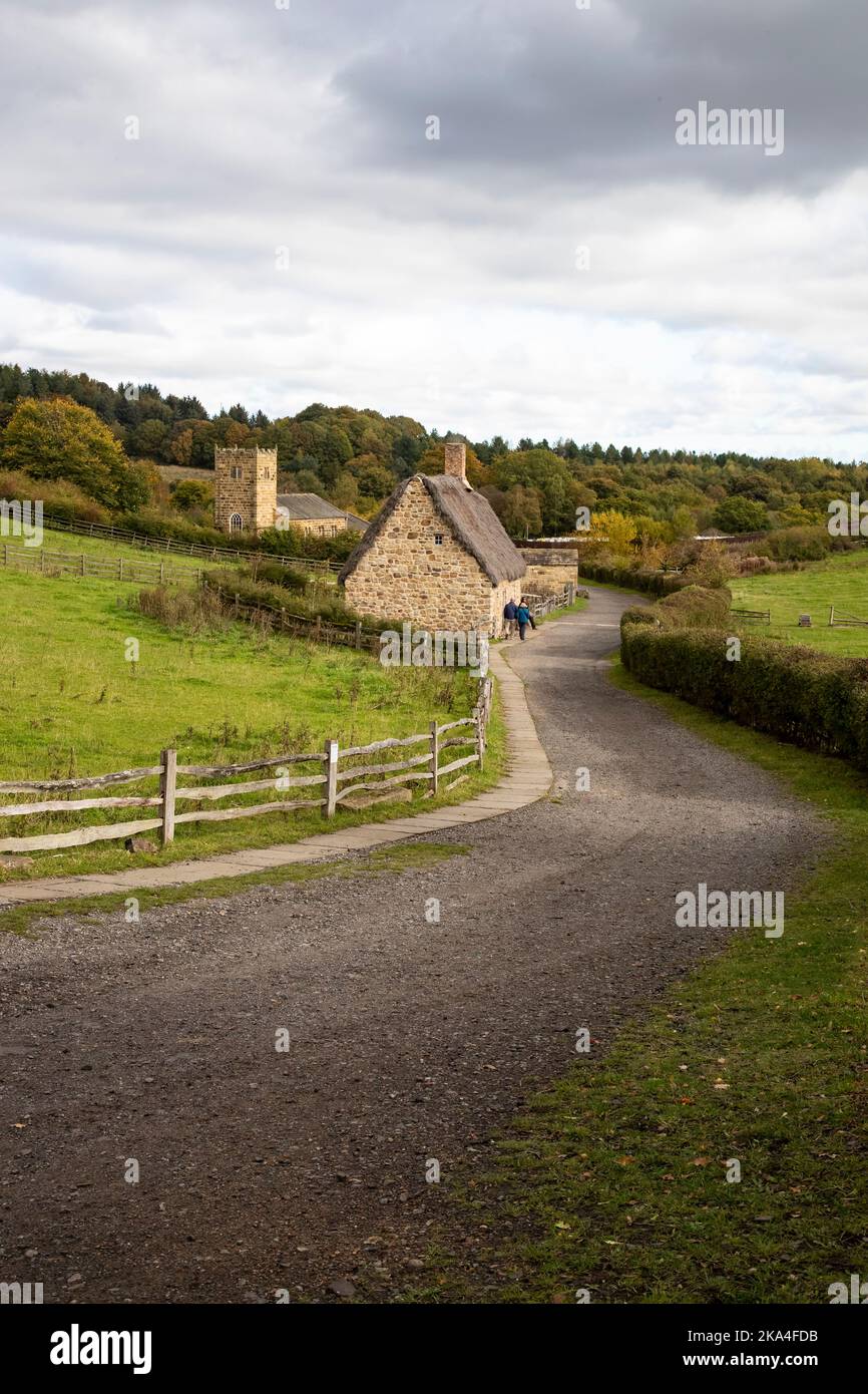A reconstructed early 19th century scene of a typical thatched cottage and church of the Georgian era at Beamish Museum, Co. Durham, Northern England Stock Photo