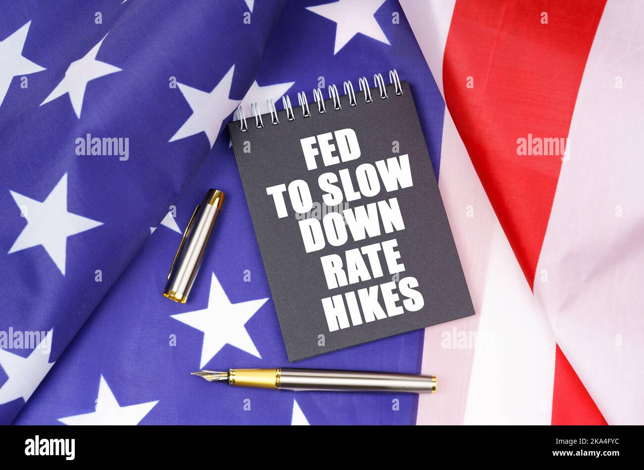 Business concept. On the American flag lies a pen and a notebook with the inscription - Fed to slow down rate hikes Stock Photo