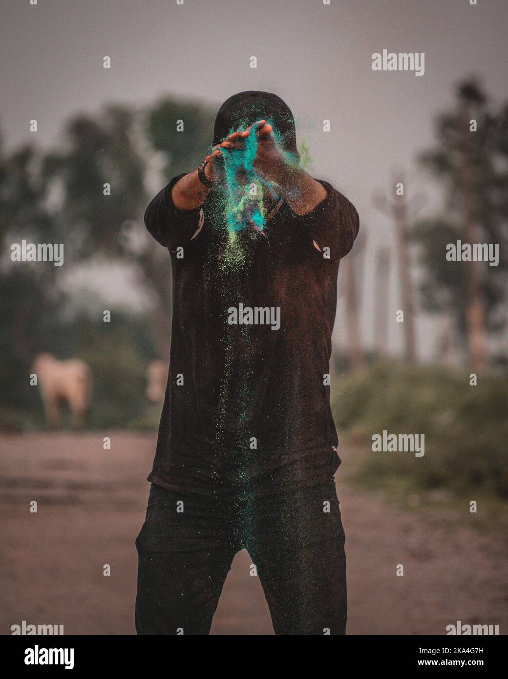 A vertical closeup of the young man spraying colored powder Stock Photo ...