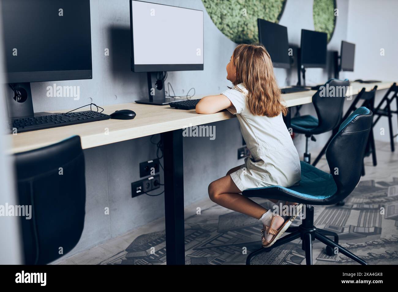 Engaged schoolgirl learning to use technology in classroom at primary ...