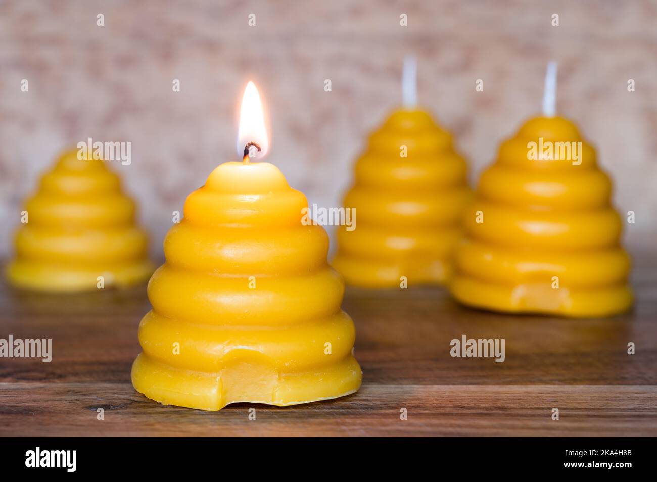 Beeswax candles shaped like skeps on wood background, front lit candle Stock Photo