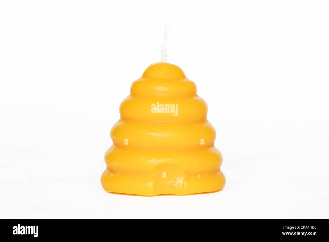 Single beeswax candle in shape of a skep on a white background Stock Photo