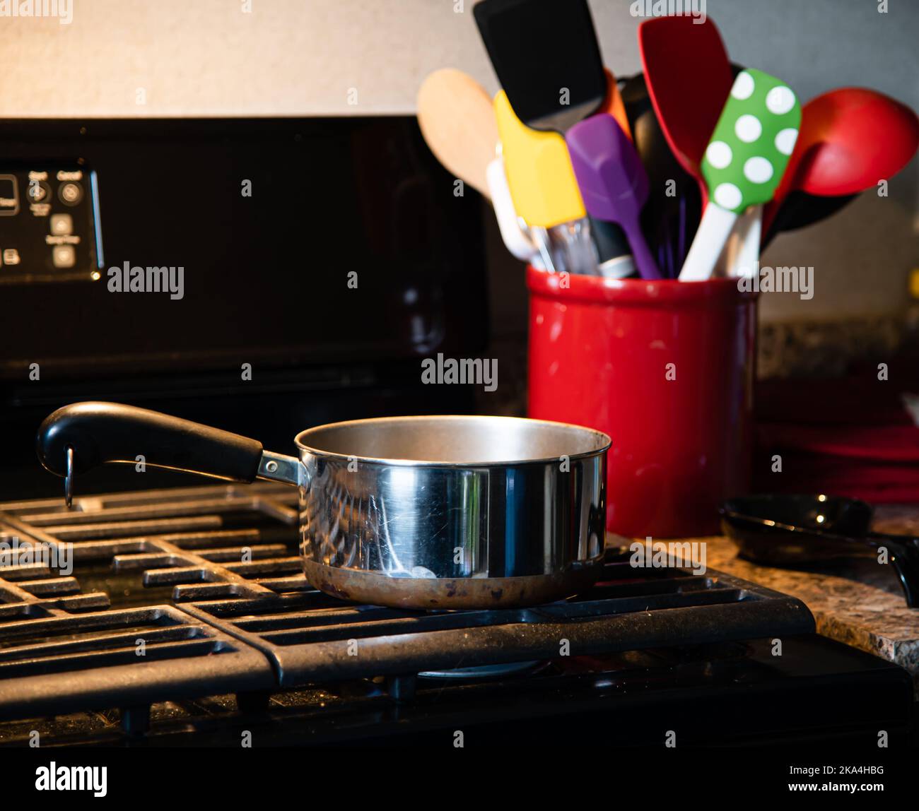 Stainless steel saucepan on a black gas stovetop with red container