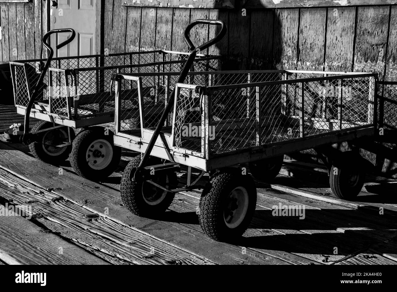 metal wire carts parked next to the outside wall, and wood boardwalk. Stock Photo
