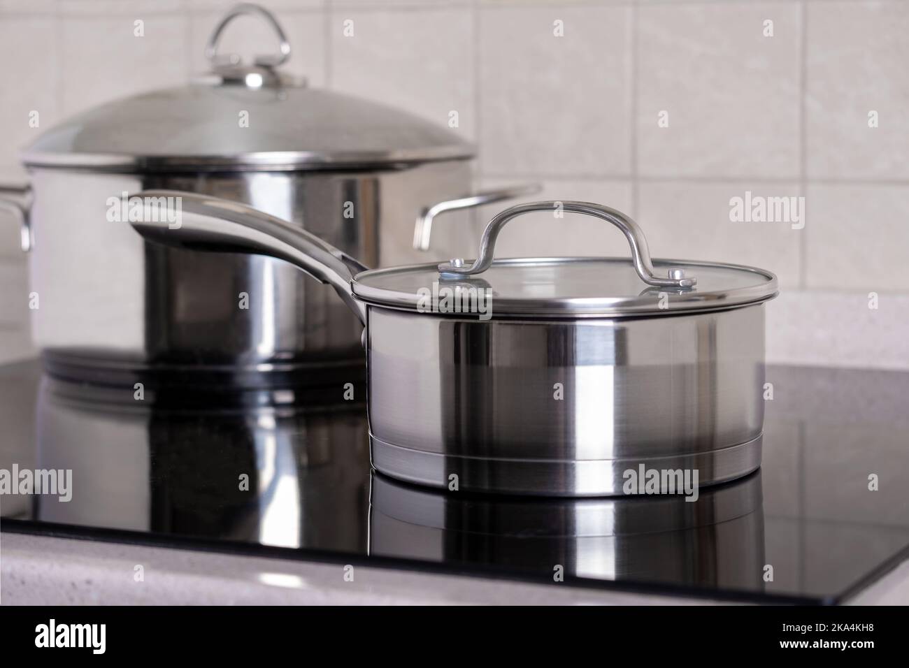 Ladle and large saucepan stand on modern stove with glassceramic hob