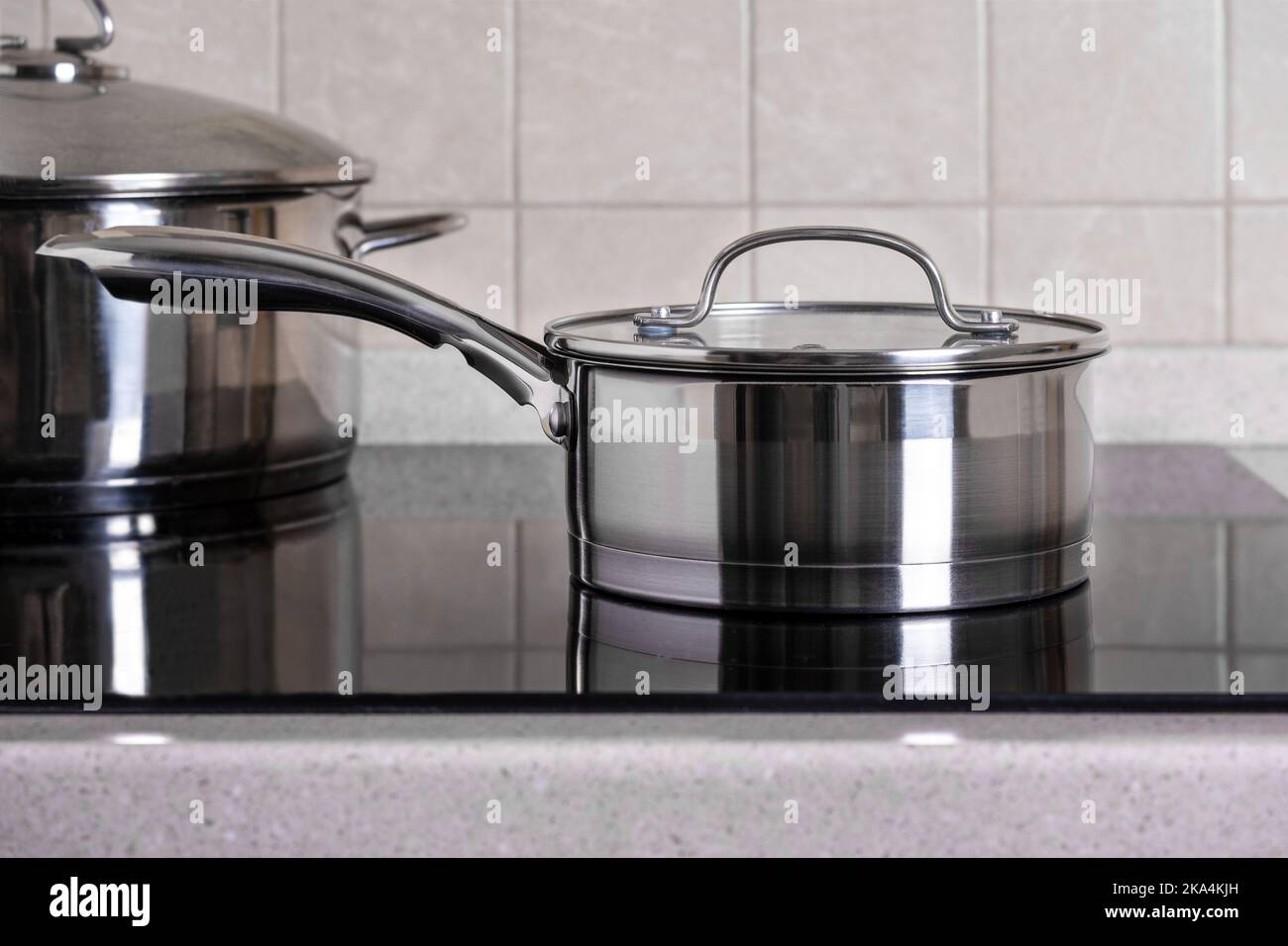 Ladle and large saucepan stand on modern stove with glassceramic hob