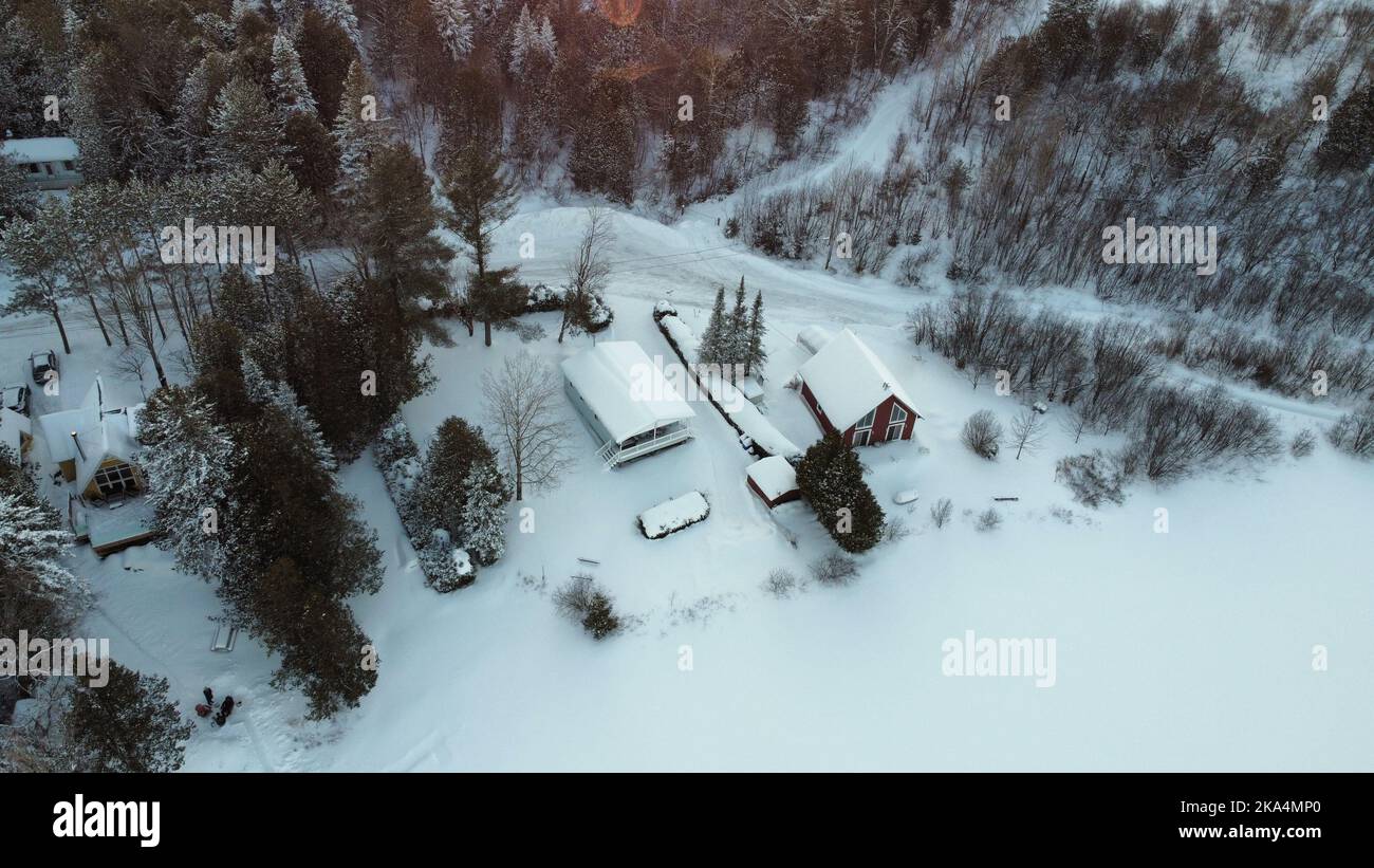 An aerial view of snowy houses on landscape field below the mountain ...