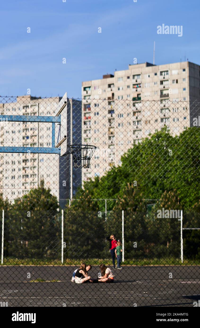 A vertical shot of a grid fence in front of a playfield with kids and ...