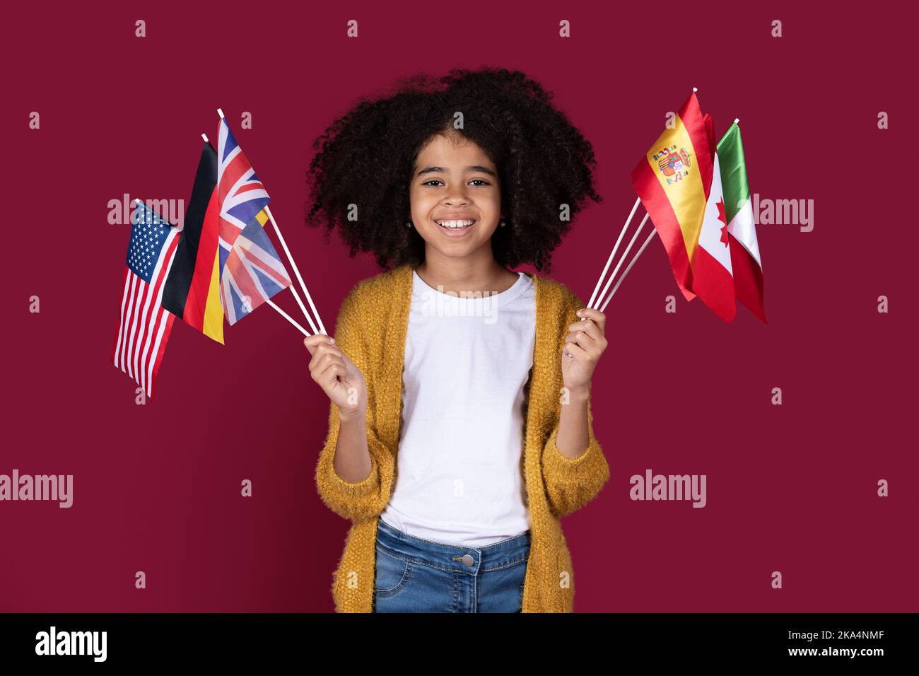 Adorable black girl schooler holding flags of various countries Stock