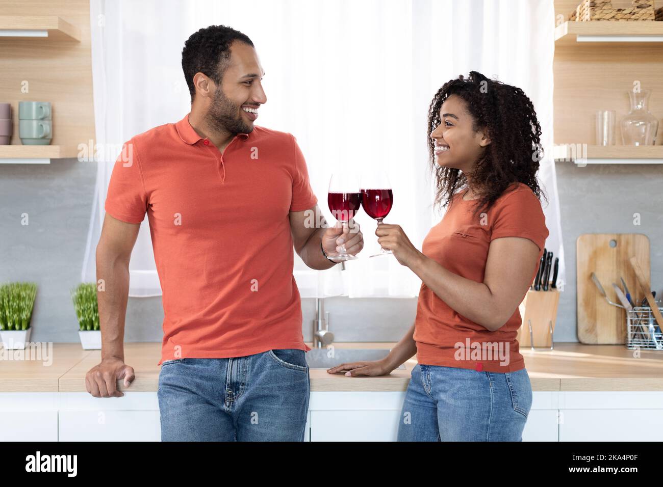 Smiling glad young black woman and man with glasses of wine enjoy holiday, spare time and celebration Stock Photo