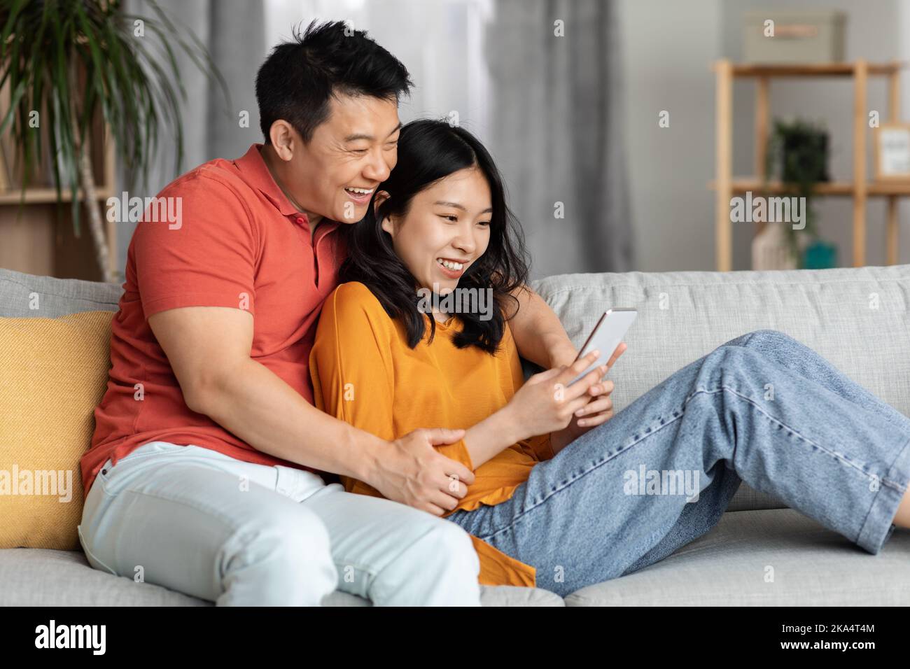 Asian couple sitting sofa using hi-res stock photography and images - Alamy