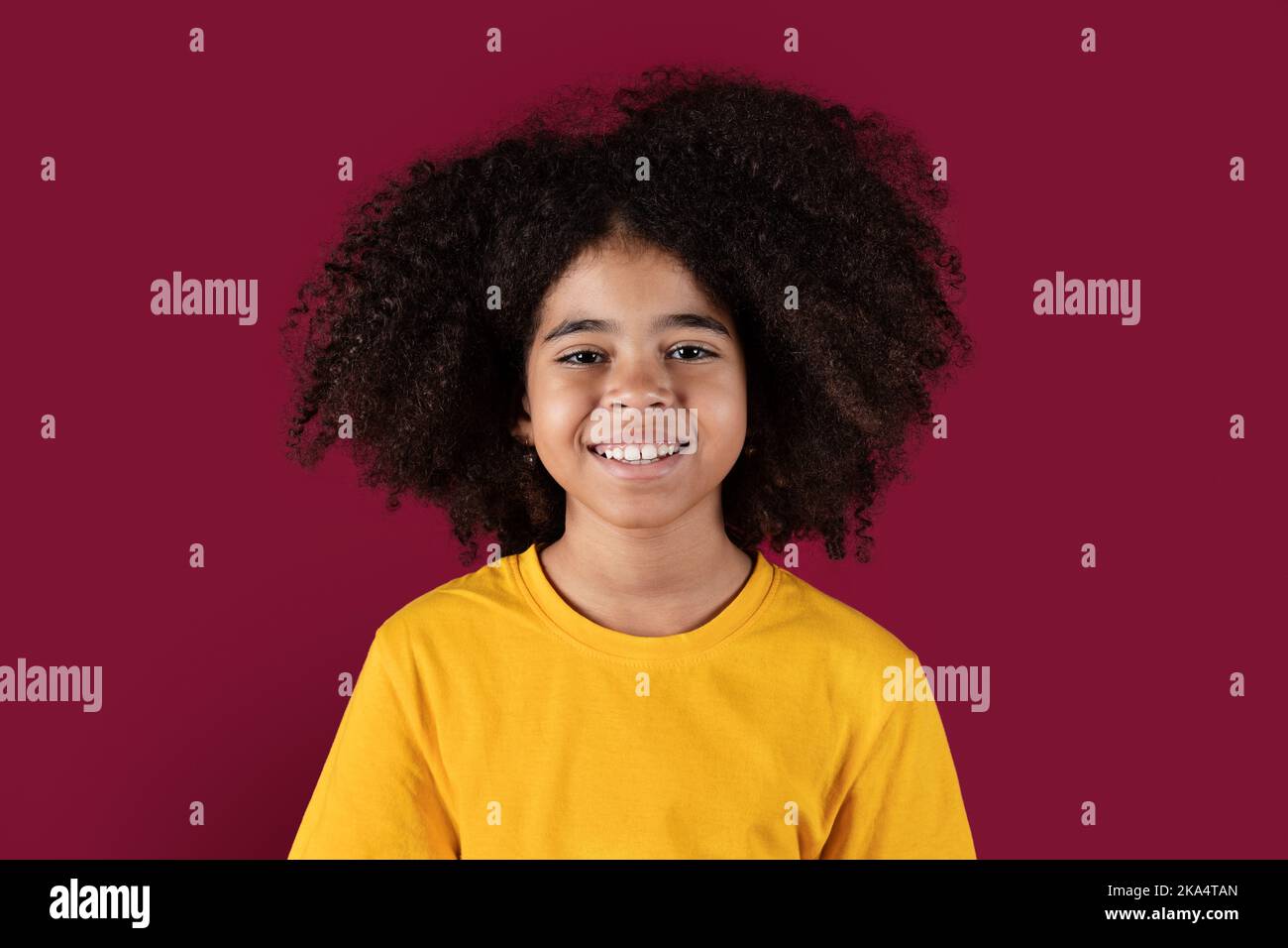 Portrait of smiling african american kid girl on burgundy background ...