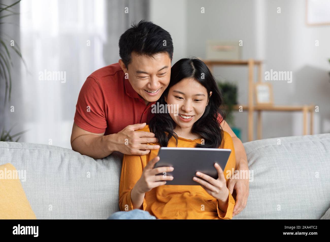 Positive chinese spouses using digital tablet, having video call Stock Photo
