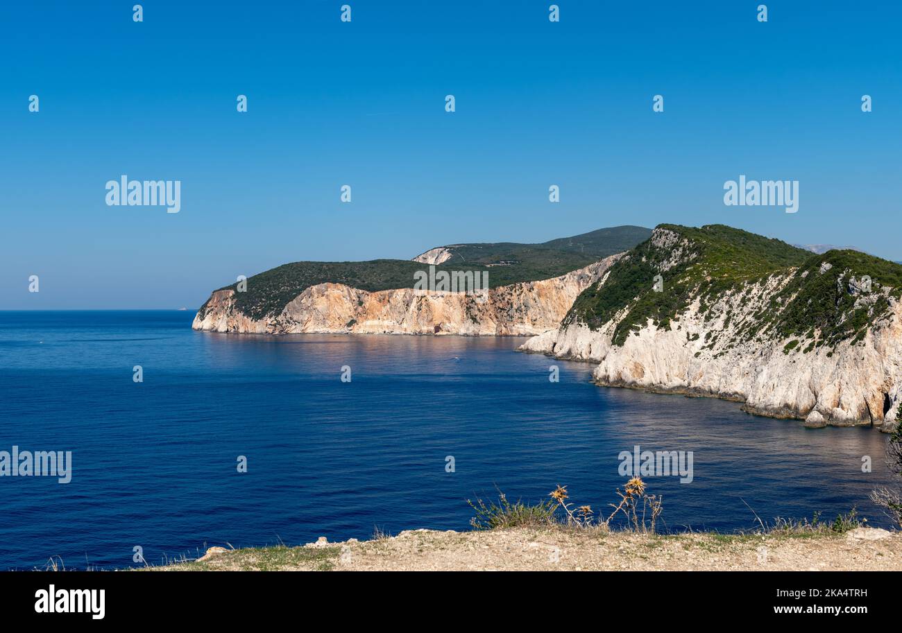 Headland cliffs sliding into deep blue sea on a beautiful cloudless day with blue sky. Stock Photo