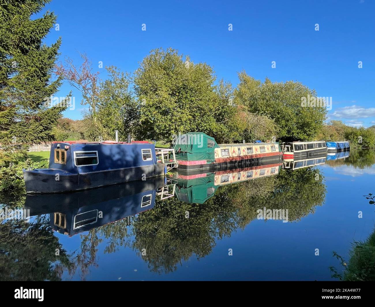 Four narrowboats moored along Grand Union Canal on a sunny autumn day near Bourne End, Hertfordshire, England, UK Stock Photo