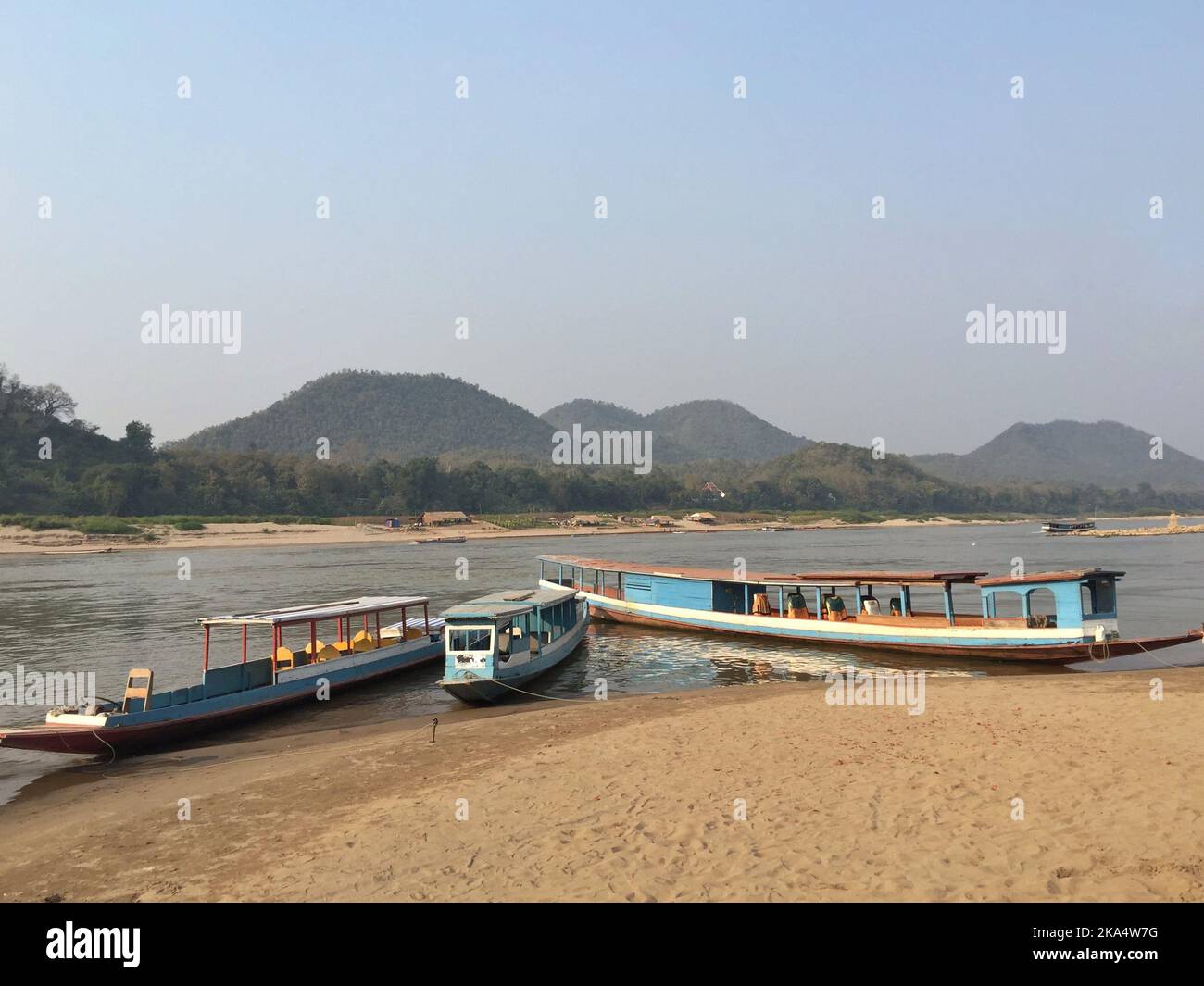 Three traditional boats moored on riverbank of Mekong river, Luang Prabang, Laos Stock Photo