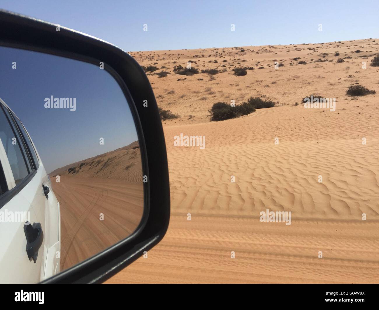 Reflection of road through sand dunes in a car wing mirror, Wahiba Sands, Oman Stock Photo
