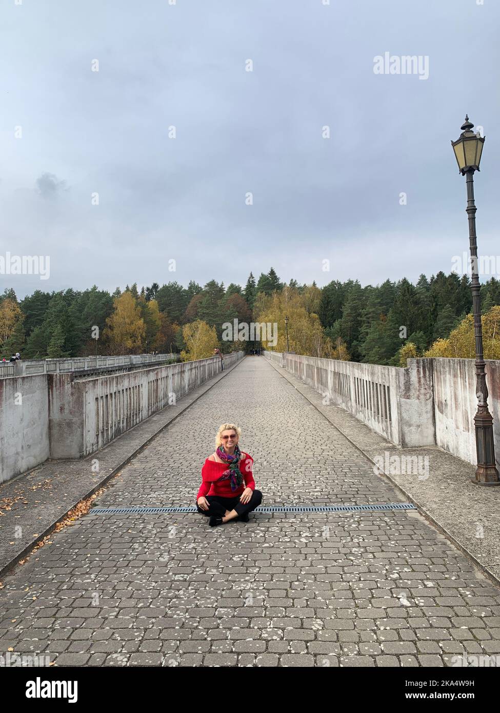 Smiling woman sitting cross-legged on a traditional aqueduct, Stanczyki, Podlasie, Poland Stock Photo