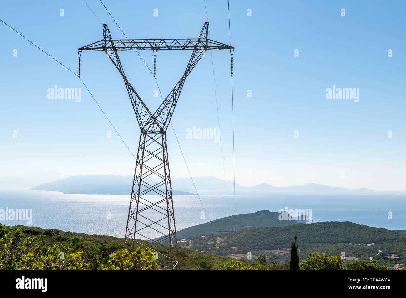 A electricity transmission tower with a view of the sea and island. Stock Photo