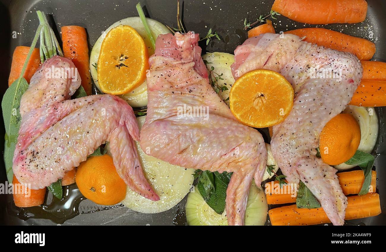 Overhead view of raw chicken wings, carrots, onions, orange, thyme and sage in a roasting pan to make a gravy Stock Photo