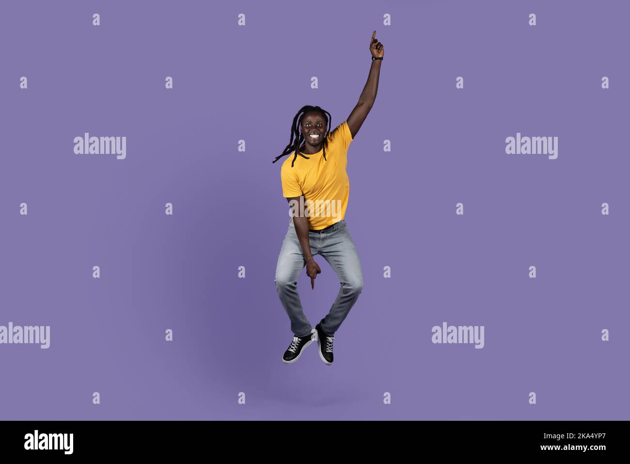 Joyful african american guy jumping over purple background Stock Photo