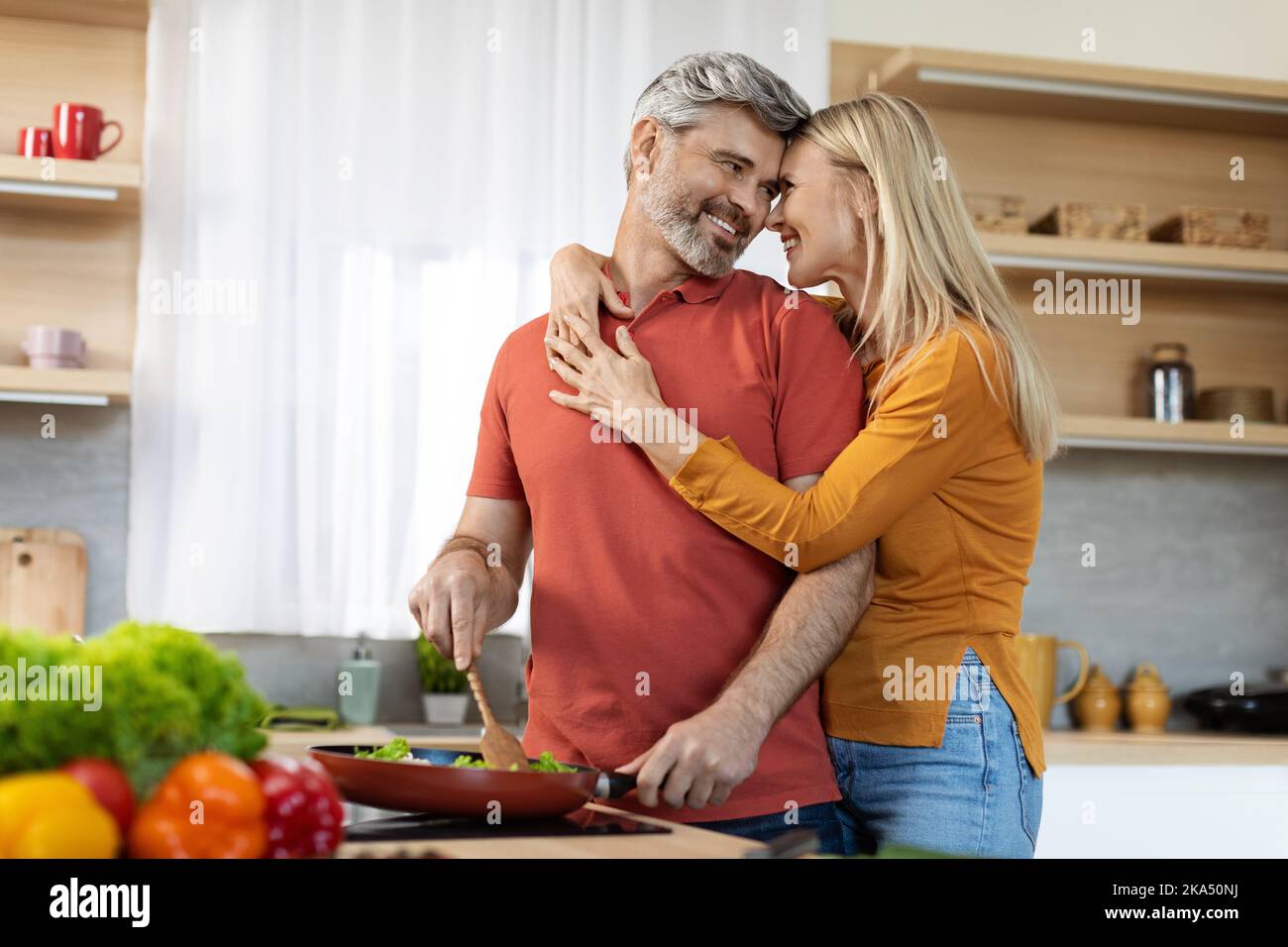Romantic spouses bonding while preparing meal together at home Stock Photo