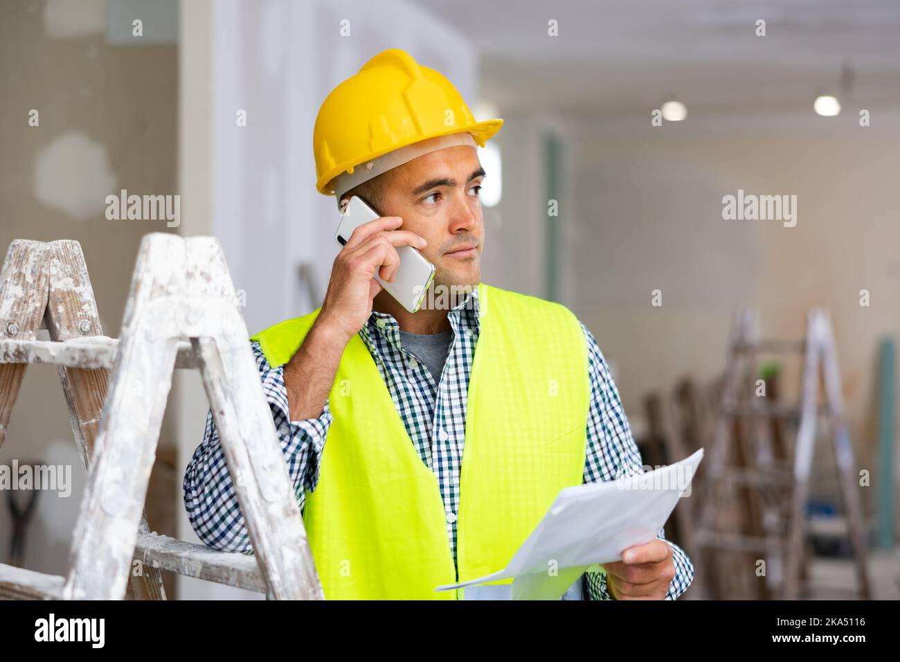 Young foreman with documents in his hands is talking on a mobile phone Stock Photo