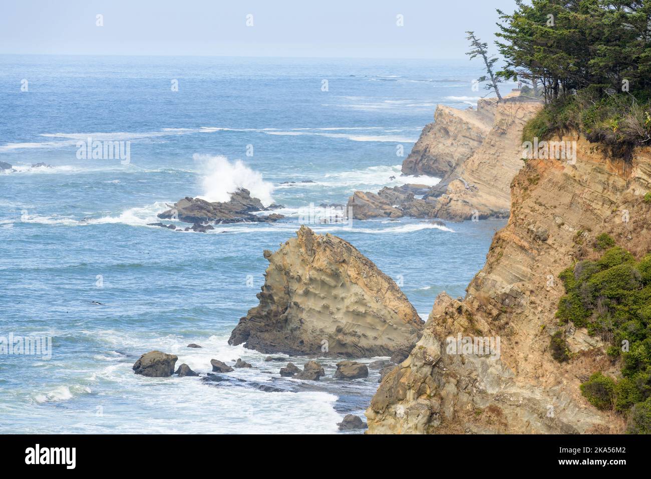 Surf on the rugged coastline of Cape Arago on the Oregon Coast with colorful cliff faces Stock Photo