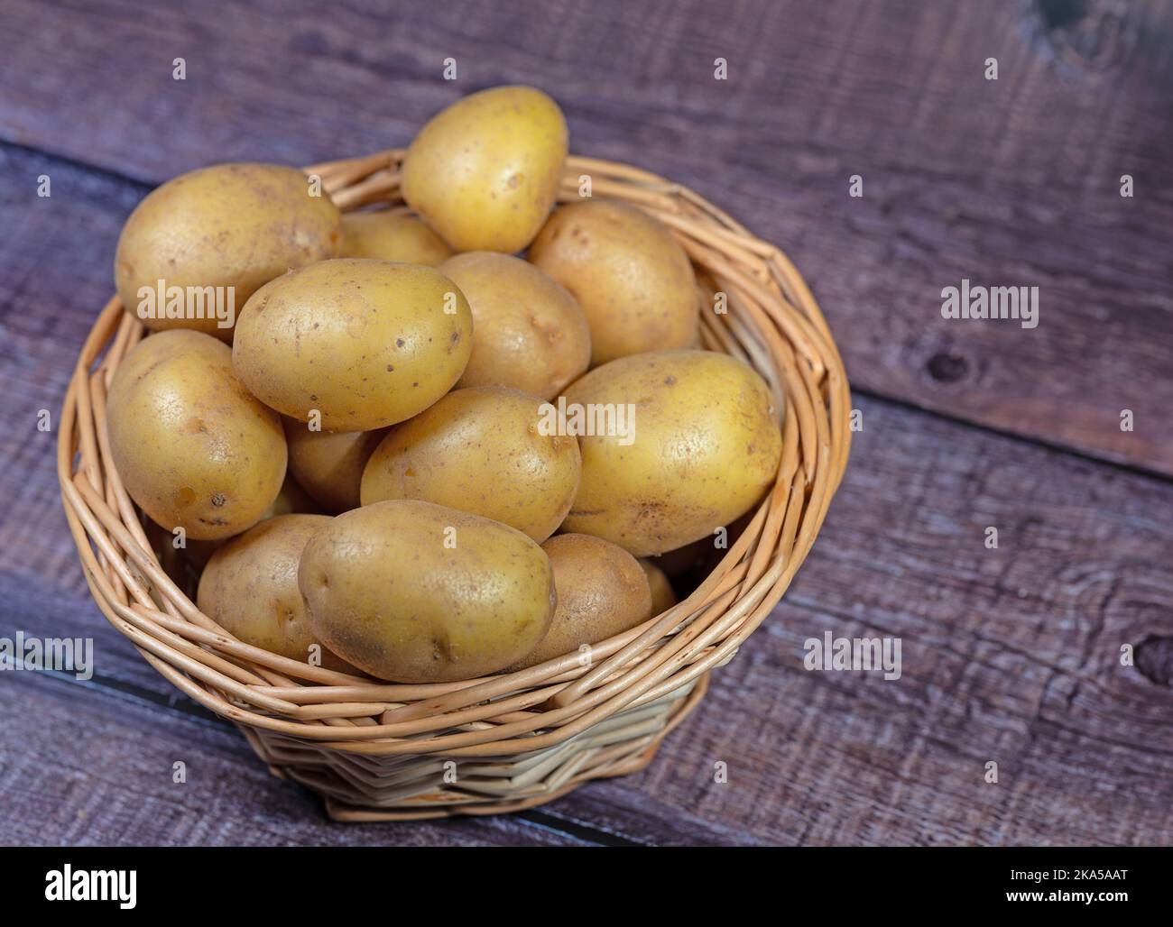 Potatoes in the basket on wooden background Stock Photo
