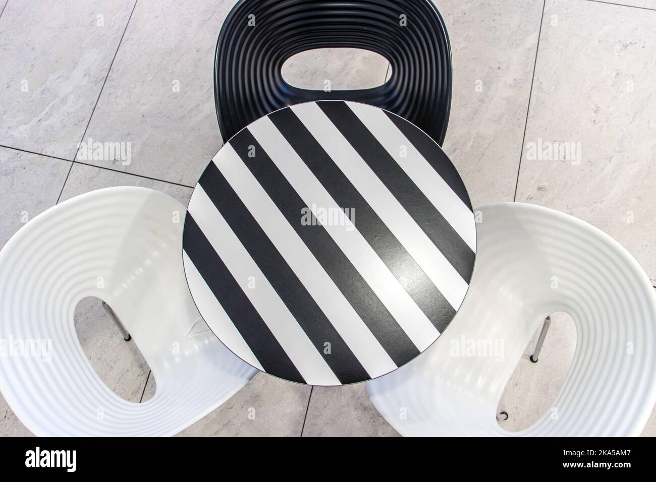 Round table with black and white stripes and empty seats, top view