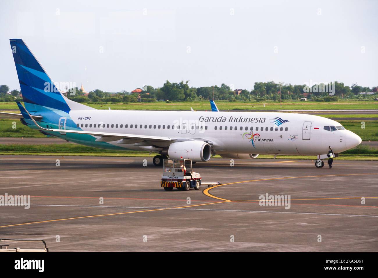 View of Garuda Indonesia airliner on runway at Juanda International Airport with clouds in blue
