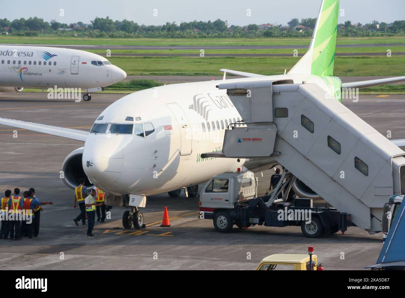 View of Garuda Indonesia low cost carrier Citilink airliner on apron with ground crew at Juanda