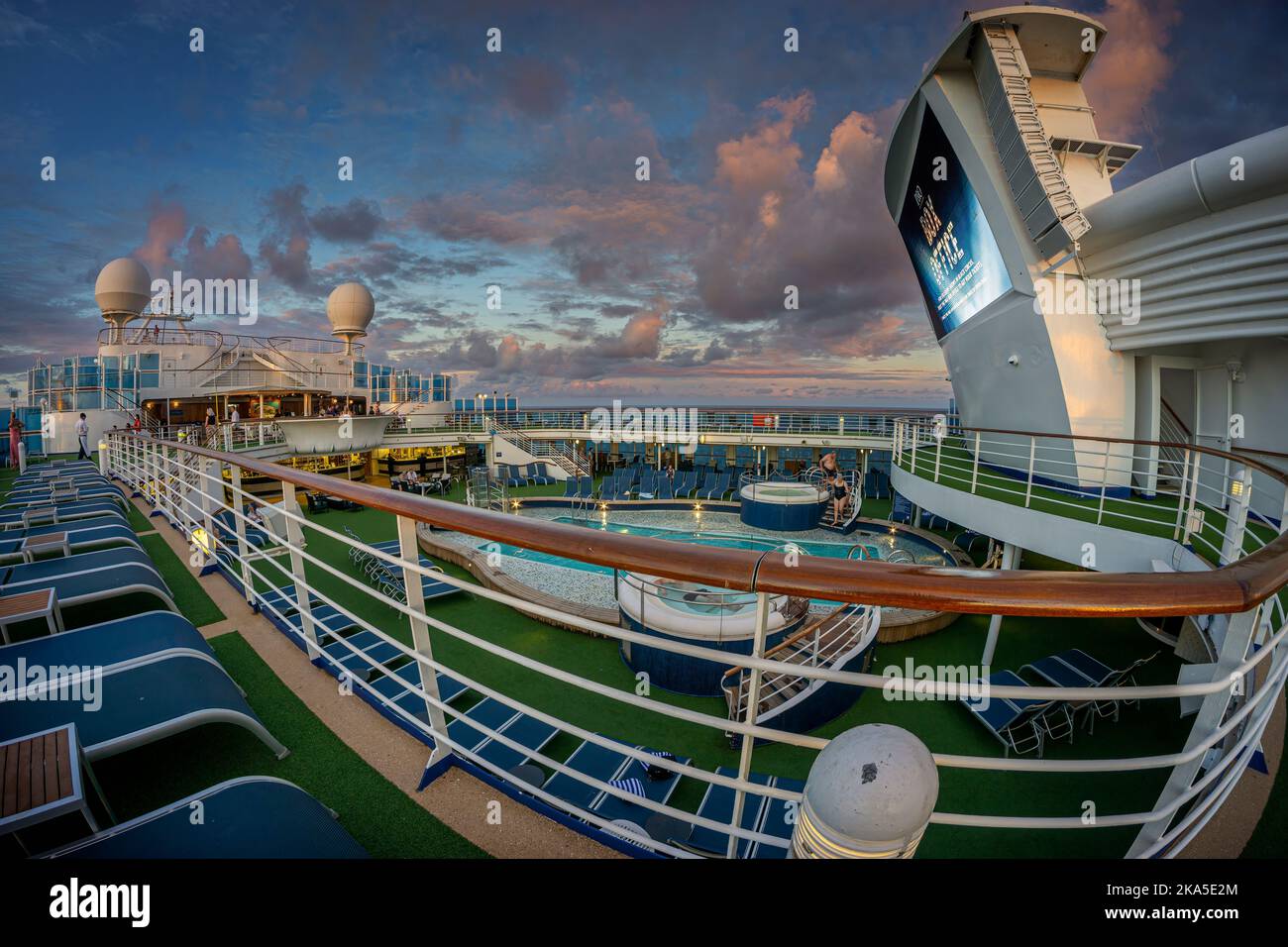 Wide angle view of entertainment deck on cruise liner at sunset with colourful clouds. South Pacific Ocean. Stock Photo