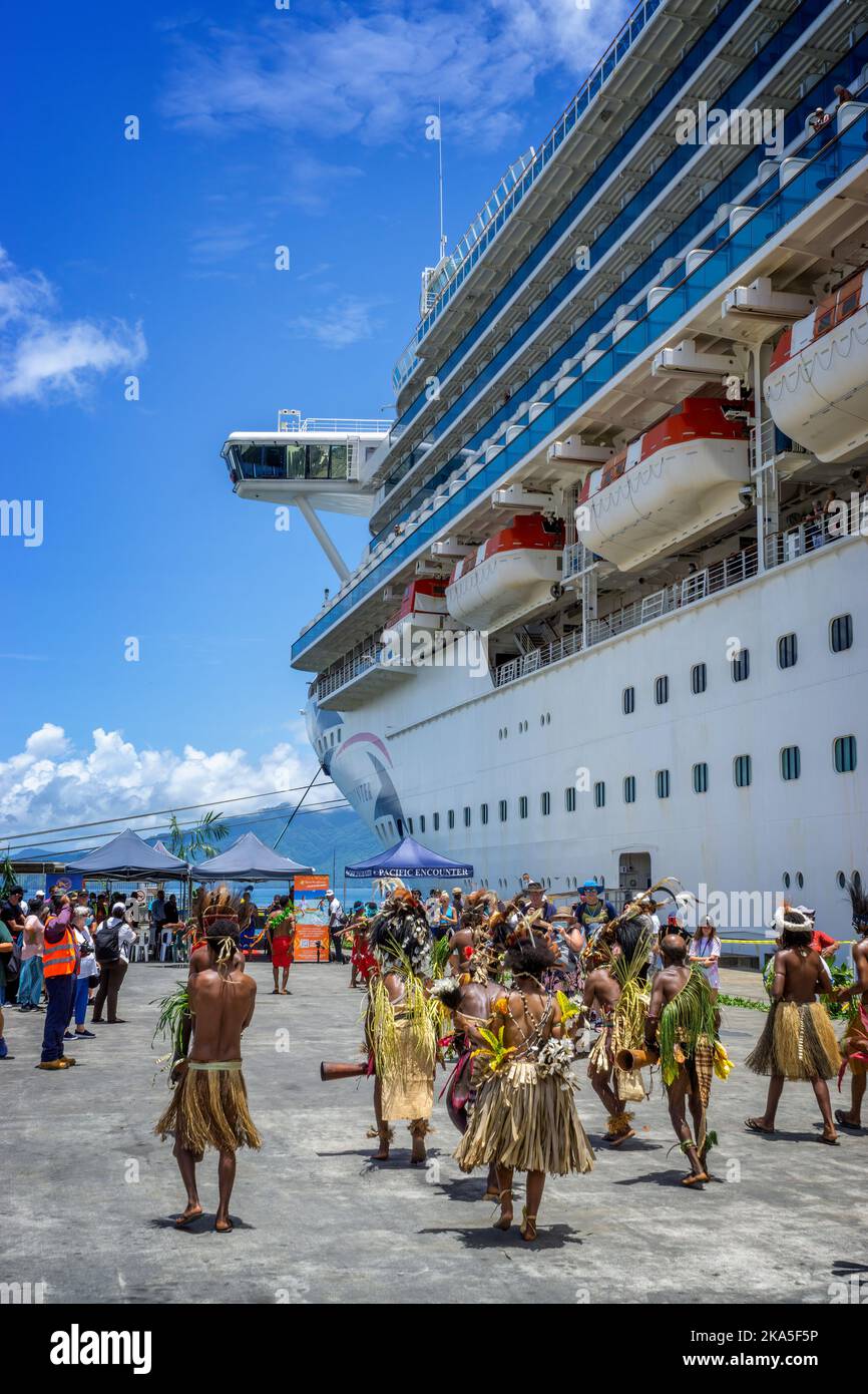 Indigenous dancers in traditional costume greet the arrival of a cruise ship, Alotau, Milne Bay Province, Papua New Guinea Stock Photo