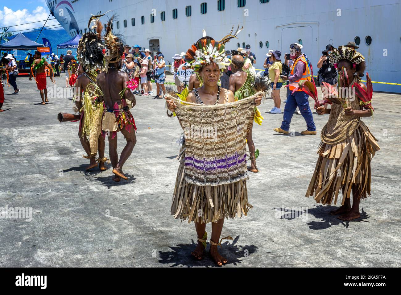 Indigenous dancers in traditional costume greet the arrival of a cruise