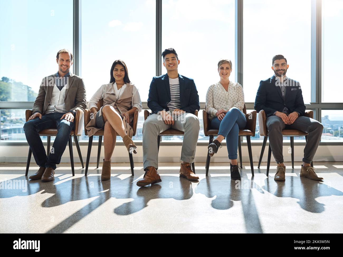 Were all in a good mood today. Portrait of a group of businesspeople sitting in line in an office. Stock Photo
