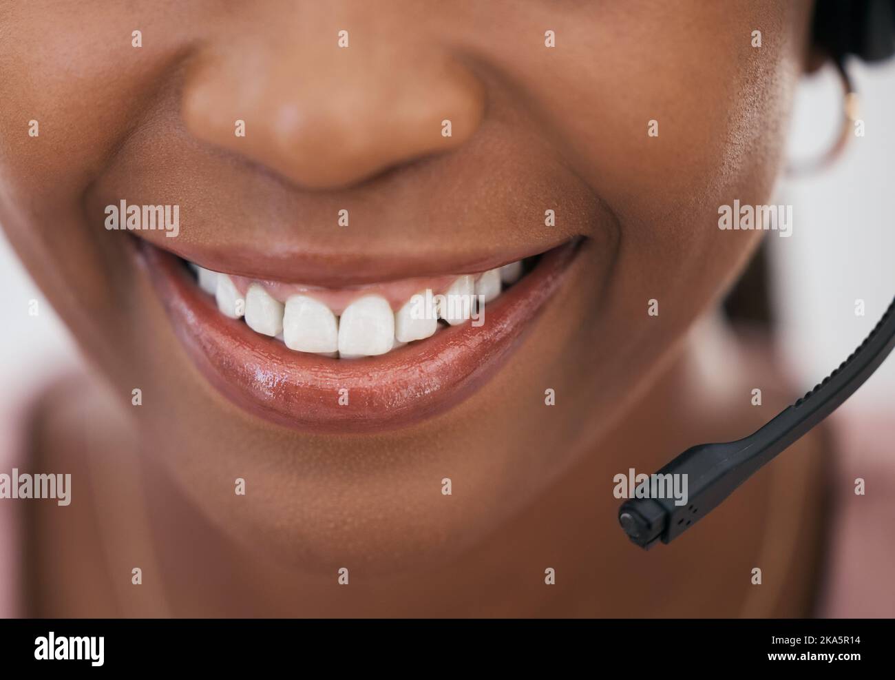 Call center consultant, black woman and smile in closeup of mouth with headset, customer service and support at help desk. Happy telemarketing agent Stock Photo